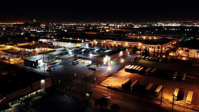Aerial view of a bus depot and parking lot illuminated at night with rows of parked buses and cars in Los Angeles, California, United States.