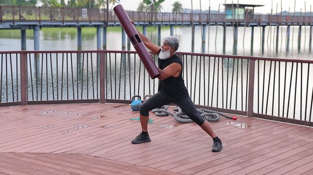 Mature Indian man with a beard exercising in a lakeside park In Singapore.
