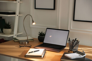 Fototapeta premium Stylish workplace with lamp, laptop and stationery indoors