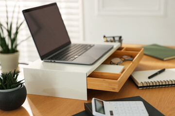 Naklejka premium Workplace with laptop on riser stand and stationery indoors, closeup
