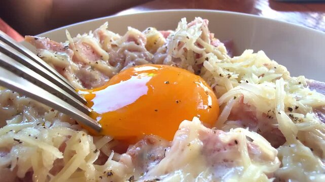 Close-up of a runny egg yolk in carbonara pasta