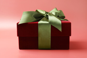 Obraz premium Gift box with green satin bow on red background, closeup