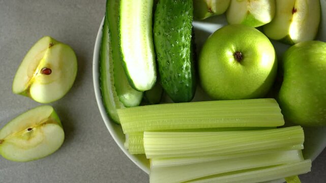 green apples, cucumbers, celery in a plate, a set of fruits and vegetables for a green smoothie