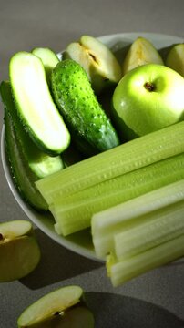 green apples, cucumbers, celery in a plate, a set of fruits and vegetables for a green smoothie