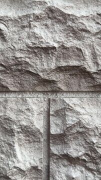 Close-up textured stone facade panels, dark brown natural stone with chiseled rough surface, modular block layout with visible