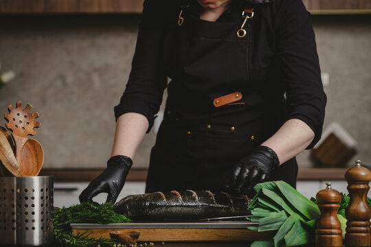 Hands of cook checking parallel cuts on raw salmon carcass. Fish quality control and premium seafood dinner preparation concept.