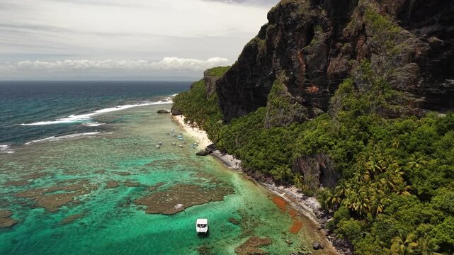 Wide drone panorama showcasing the full beauty of Fronton Beach, cliffs, palms and turquoise waters.