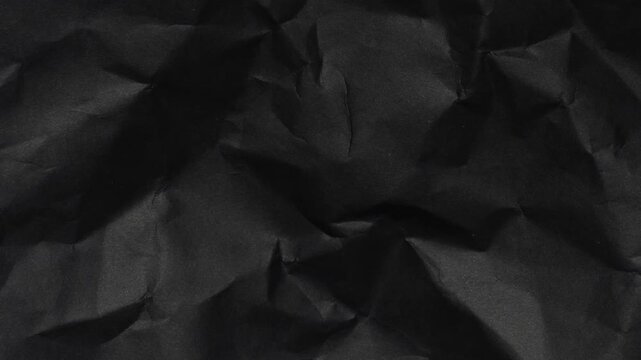 grunge crumpled black paper texture. worn out dark texture with shadows and light