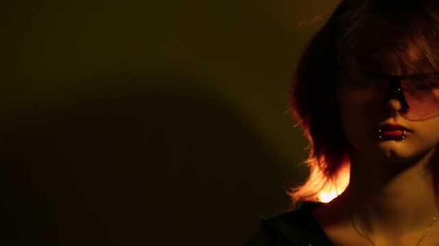 Portrait of a young long hair woman posing in studio creative light in protective sport fashion sunglasses. Expression girl face with piercing on lips looking. Close-up head art move