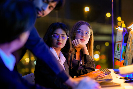 Data science team responding to live alerts on the big screen in a global surveillance center, double-checking results, in a scene about analytics and focused mission-critical mood.