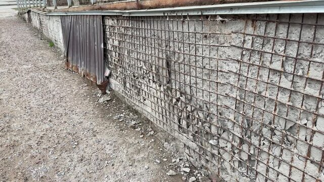 Rusty metal cladding and mesh on apartment extension showing heavy corrosion, flaking paint and exposed brick, twisted mesh