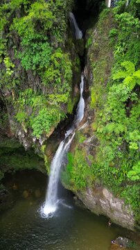 An breathtaking drone aerial shot showcasing the magnificent Breezes Waterfall in Cuetzalan, Puebla, Mexico. Lush green jungle surrounds the cascading water falling into a natural pool below.