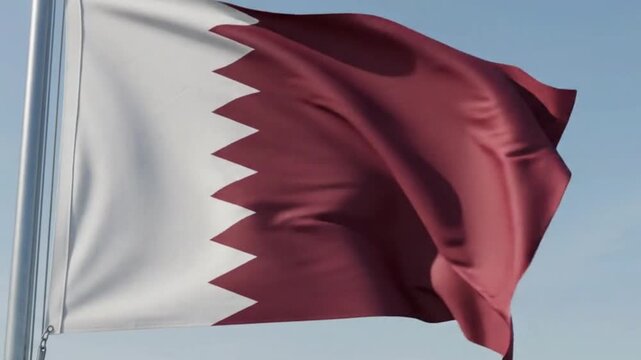 National flag of qatar waving in the wind against a clear blue sky