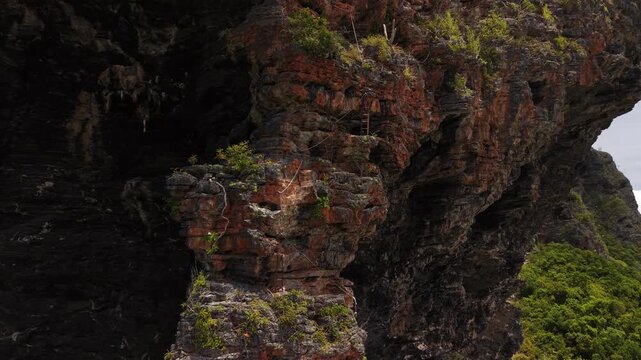 Drone close-up showcasing the rugged texture and geological formations of Fronton Beach cliffs.