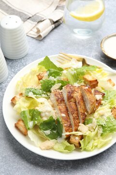 Delicious Caesar salad with chicken served on grey table