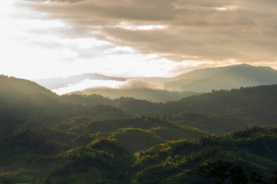 Beautiful landscape foggy hills twilight time. Blue golden sky sunrise dramatic beautiful landscape mountain. Dawn sky gold dusk time cloudscape with sunlight. Dramatic sunset over mountain landscape