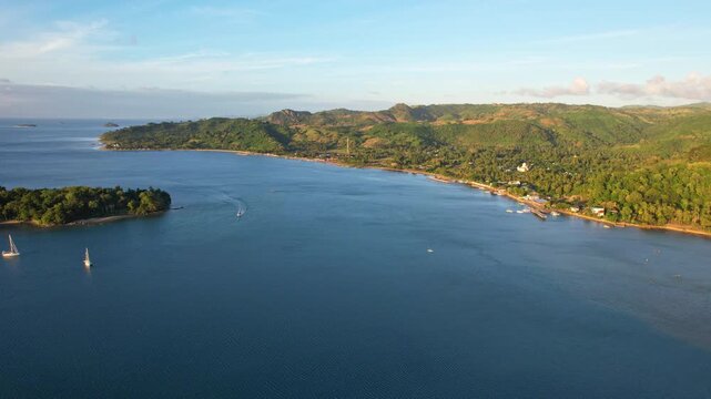 Aerial drone footage of Tembowong harbor bay, in West Sekotong, Lombok island, Indonesia, with Gili Gede touristic paradise island aside, at golden sunset, with mountains and beach, boats