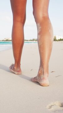 Woman feet and legs walking on beach at sunset. Closeup of beautiful girl in summer. Vertical video. Video is unretouched. Raw footage