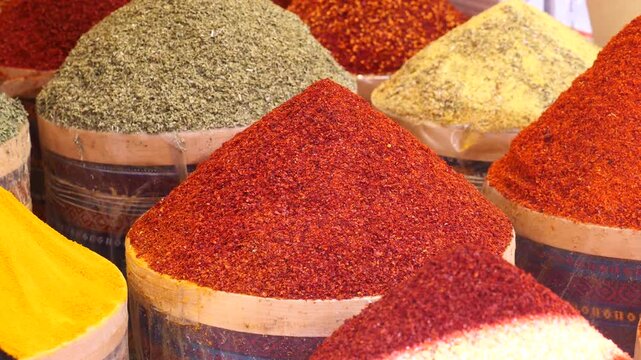 A vibrant assortment of colorful ground spices and seasonings in large wooden barrels at a bustling turkish market stall