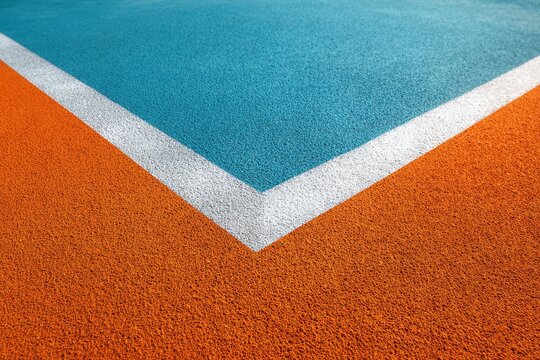 Abstract corner view of a brightly colored outdoor sports court surface with white line markings athletic playground recreation synthetic pavement abstract geometric contrast perspective