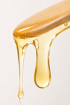 Golden Depilation Wax Dripping from Wooden Spatula