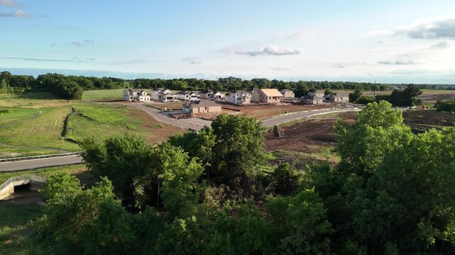 Drone perspective of a new residential housing development under construction encroaching on green farm fields, exploring suburban sprawl themes