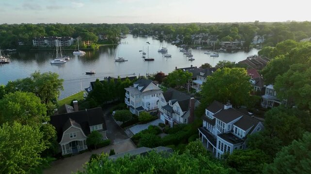 Beautiful, old houses nestled in the woods, with a lagoon behind them featuring spectacular yachts and boats at sunset