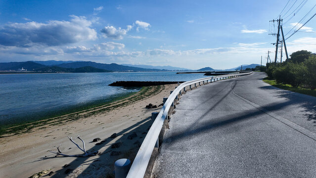 Scenic view of an empty coastal road with guardrail along the blue sea.