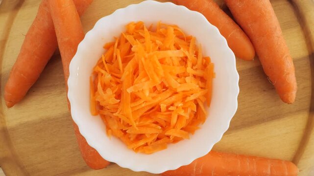 Fresh grated carrot salad rotating on wood
