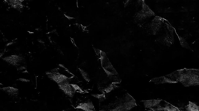 Dark charcoal paper texture with dramatic light shadows creating an abstract moving surface animation video clip