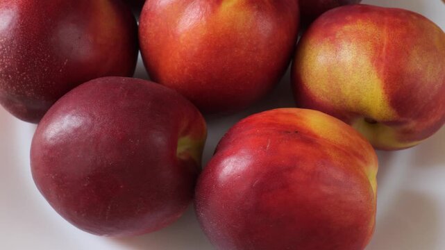 Ripe nectarine peaches rotating on a white background