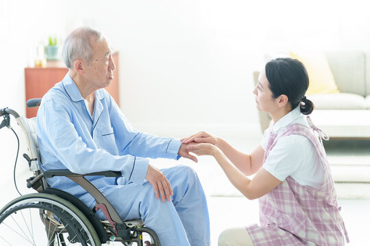 車椅子に乗った高齢者をサポートする介護士
