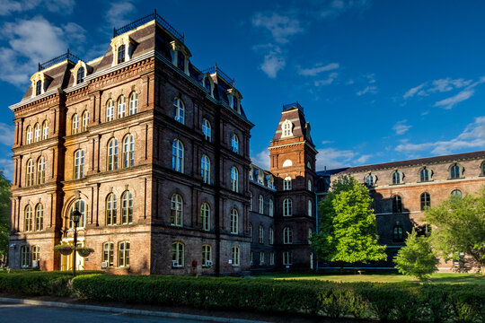Poughkeepsie, NY - US - Jun 15, 2026 Sunlit view of Vassar College featuring historic red-brick architecture, mansard roofs, and lush green grounds under a vivid blue summer sky.