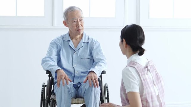 車椅子に乗った高齢者のサポートをする介護士