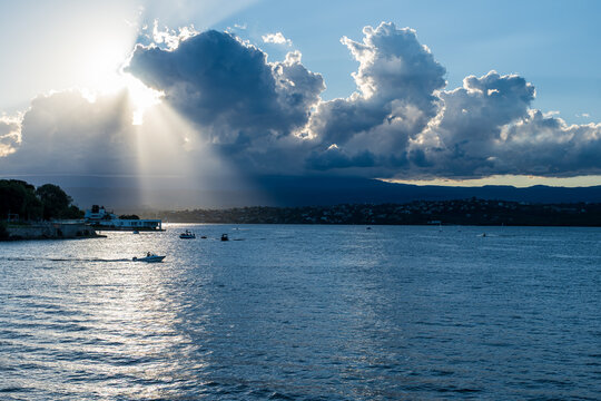 Lancha navegando en un lago bajo un imponente haz de luz solar entre las nubes