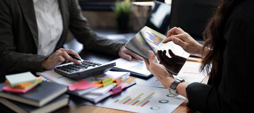 Close up of businesswomen using digital tablet and calculator analyzing financial charts