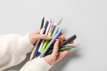 Naklejka premium Female hands with many different pens on grey background