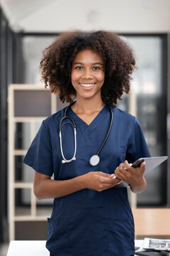 Portrait of smiling young African American female doctor holding digital tablet