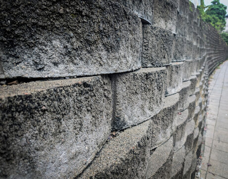  Close-up of a textured grey concrete block retaining wall in a garden or urban setting.