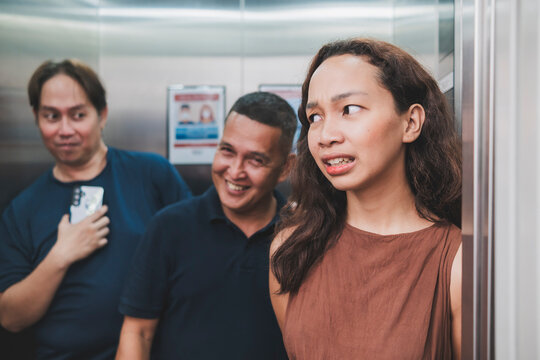 A young woman feels uneasy and intimidated while standing inside an elevator with two creepy men showing unwanted interest in her.