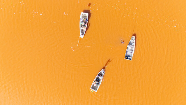 Aerial view of Lake Retba with small wooden boats and workers harvesting salt in the vibrant pink water in Rufisque, Dakar Region, Senegal.
