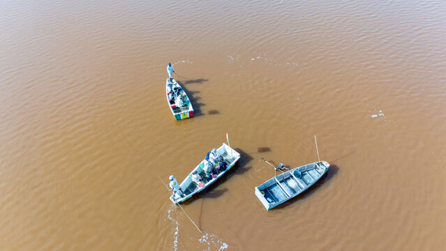 Aerial view of Lake Retba with small wooden boats carrying fishermen across the pinkish water in Rufisque, Dakar Region, Senegal.