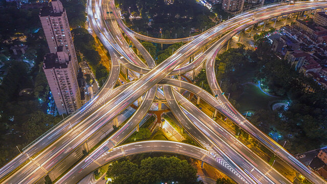 Aerial view of Yan'an Elevated Road at night with light trails from heavy traffic, surrounded by urban buildings and greenery in Shanghai, Shanghai, China.