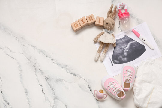 Composition with baby shoes, sonogram image, pregnancy test and word GIRL on grunge white background