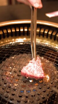 Raw Wagyu Beef Placed on Hot Charcoal Grill with Tongs