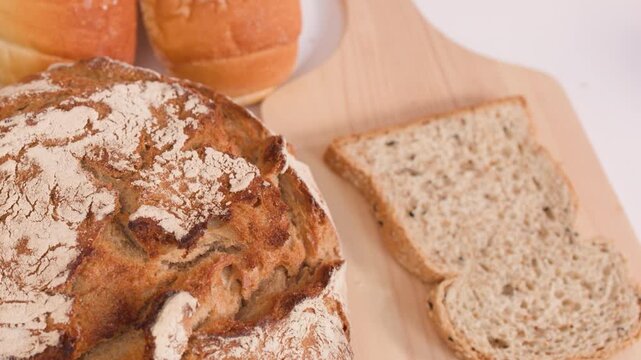 Hand Placing Fresh Multigrain Bread Slice on Wooden Cutting Board