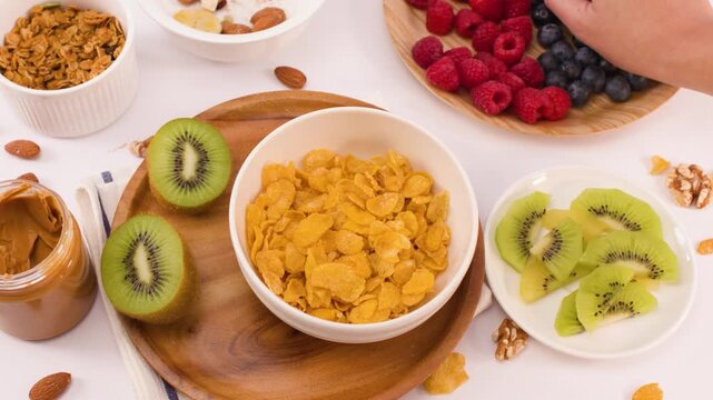 Hand Adding Fresh Blueberries to a Bowl of Corn Flakes