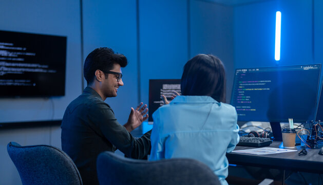 Professional IT specialist and programmer working on software development, Male developer talking with female colleague about computer code, Modern coding team and technology collaboration concept