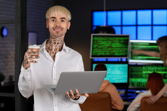 Male programmer with laptop and cup of coffee in office at night