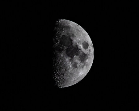 A half moon in a deep black sky with dramatic sunlight